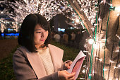 クリスマスライトの下でクリスマスカードを開く若い女性