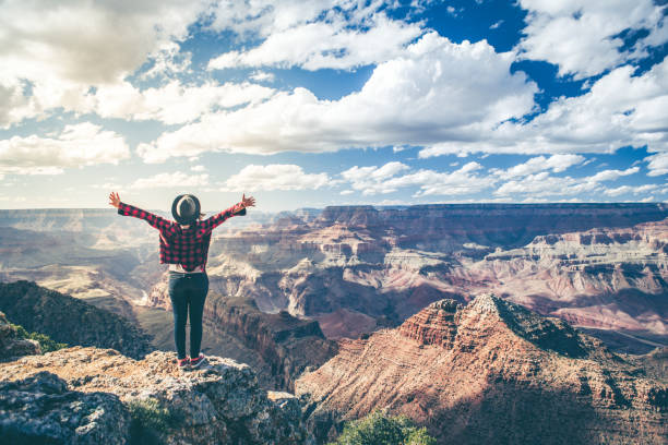 Young Woman Overlooking The Grand Canyon A dramatic overlook over the grand canyon in arizona USA. A Young woman looks over the edge in amazement. grand canyon stock pictures, royalty-free photos & images