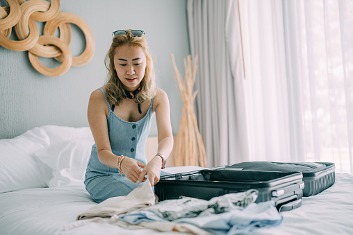 Young woman packing suitcase