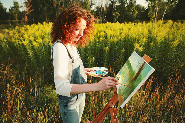 Young woman painting landscape in open air. stock photo