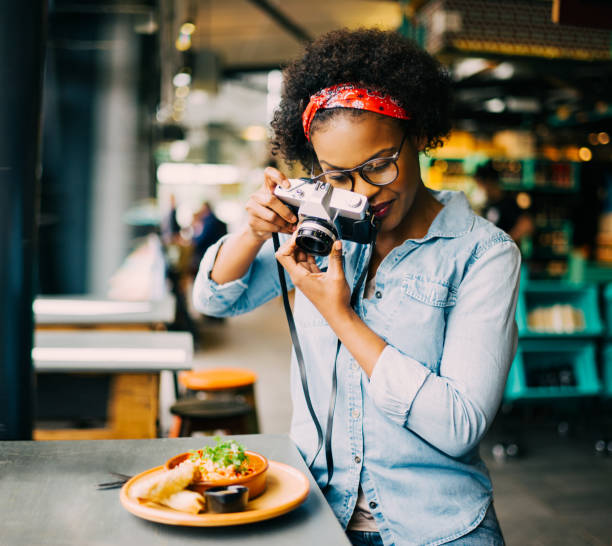 Young woman photographing her food on a cafe counter stock photo