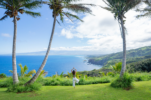 She balances in tree pose and looks out across the Pacific Ocean below
