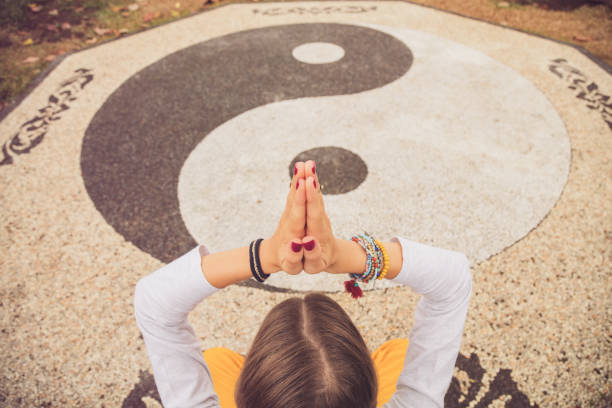 Young woman practicing yoga - meditation on the yin yang sign. stock photo