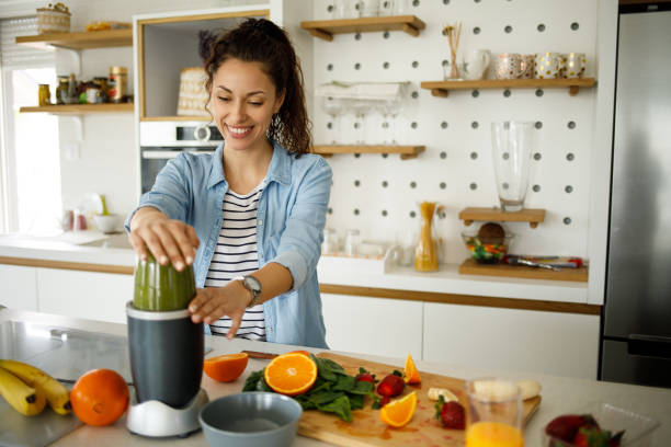Young woman preparing a green smoothie at home Young woman preparing a green smoothie at home drinking smoothie stock pictures, royalty-free photos & images