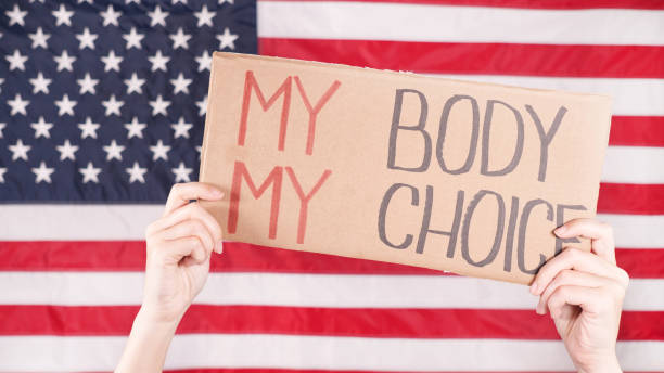 젊은 여성 시위자는 백그라운드에서 미국 국기에 대한 my body my choice 표지판이 적힌 골판지를 들고 있습니다. 낙태 금지법에 항의하는 소녀. 페미니스트 권력. 평등 한 기회 여성 권리 갈대. - roe v wade 뉴스 사진 이미지