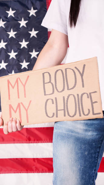 젊은 여성 시위자는 백그라운드에서 미국 국기에 대한 my body my choice 표지판이 적힌 골판지를 들고 있습니다. 낙태 금지법에 항의하는 소녀. 페미니스트 권력. 평등 한 기회 여성 권리 갈대. - roe vs wade 뉴스 사진 이미지