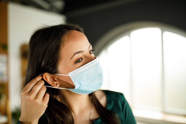 Young woman putting on a protective face mask stock photo