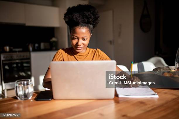 Young woman reading from the computer and taking notes at her notebook
