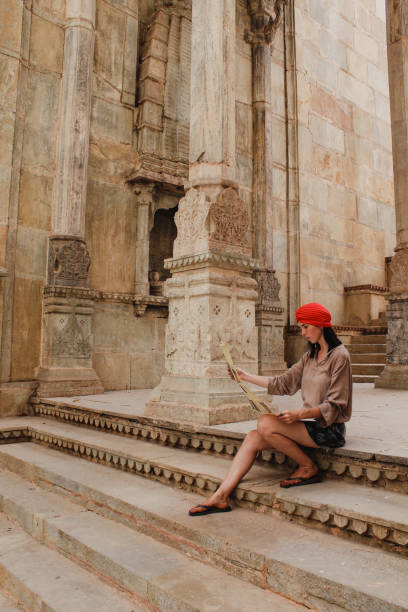 Young Woman Reading Map in Bundi Temple Young traveler is sitting on some steps in Bundi wearing a red turban, looking at a map for directions. kota rajasthan stock pictures, royalty-free photos & images