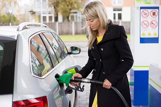 young woman refilling petrol in gas station - tanken stockfoto's en -beelden