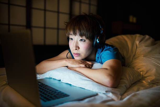 young woman relaxing at home - watching tv stockfoto's en -beelden