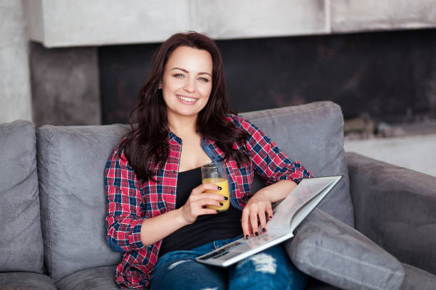 Young Woman Relaxing at Home with a Glass of Orange Juice. Beautiful...
