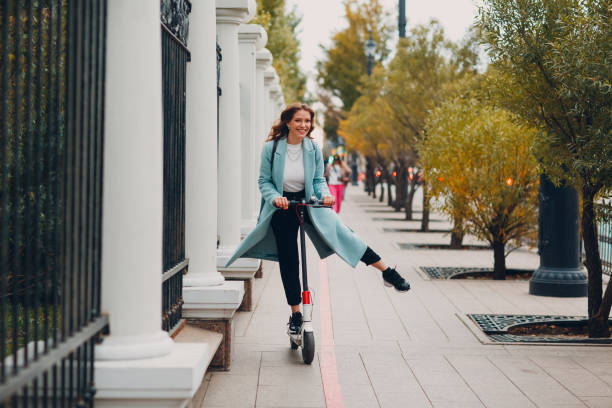 de jonge vrouw berijdt elektrische scooter bij de stadsstraat - elektrische step stockfoto's en -beelden