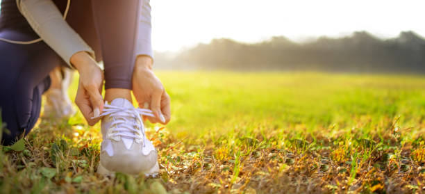 young woman runner tying her shoes preparing for a jog outside at morning - woman walk imagens e fotografias de stock