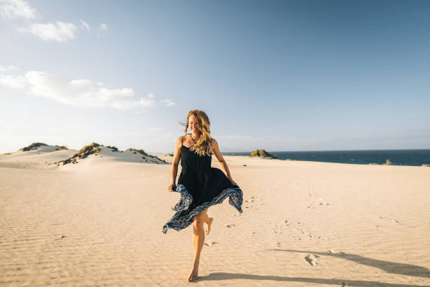 Young woman runs along coastal sand dune in Lanzarote, Canary Islands stock photo