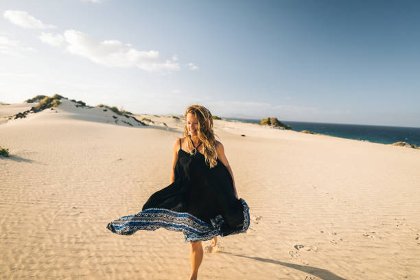 Young woman runs along coastal sand dune in Lanzarote, Canary Islands stock photo
