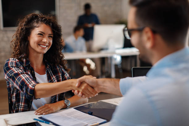 Young woman signing contracts and handshake with a manager Young woman signing contracts and handshake with a manager hiring stock pictures, royalty-free photos & images