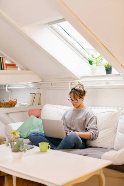 Young woman sitting and using laptop at home stock photo