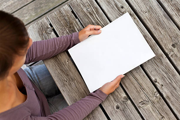 Young woman sitting at wooden table with a booklet stock photo