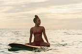 波を待っているサーフボードに座っている若い女性