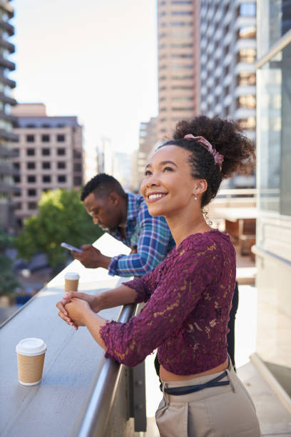 A young woman smiles and looks at the view on her coffee break in the city stock photo