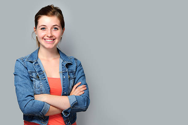 young woman smiling wearing denim jacket with arms folded - portrait girl stockfoto's en -beelden