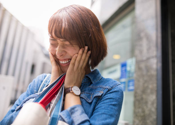 Young woman smilying with hands on cheek Young woman smilying with hands on cheek shy japanese woman stock pictures, royalty-free photos & images