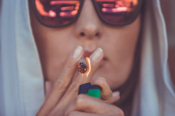 Young woman smoking marijuana joint - medical marijuana use and legalization of cannabis concepts - closeup-of lighting a weed cigarette in Amsterdam (Holland - Netherlands) stock photo