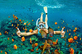 Happy family - girl in snorkeling mask dive underwater with tropical fishes in coral reef sea pool. Travel lifestyle, water sport outdoor adventure, swimming lessons on summer beach holiday with kids