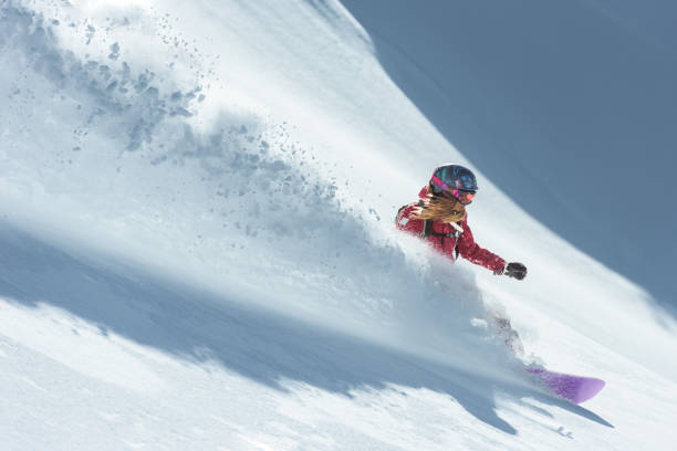 Young woman snowboarding in fresh snow stock photo
