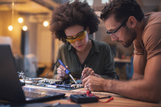 Young woman soldering a circuit boards in her tech office stock photo