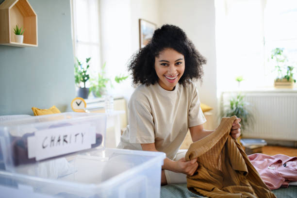 Young woman sorting wardrobe indoors at home, charity donation concept. Happy young woman sorting wardrobe indoors at home, charity donation concept. arrangement stock pictures, royalty-free photos & images