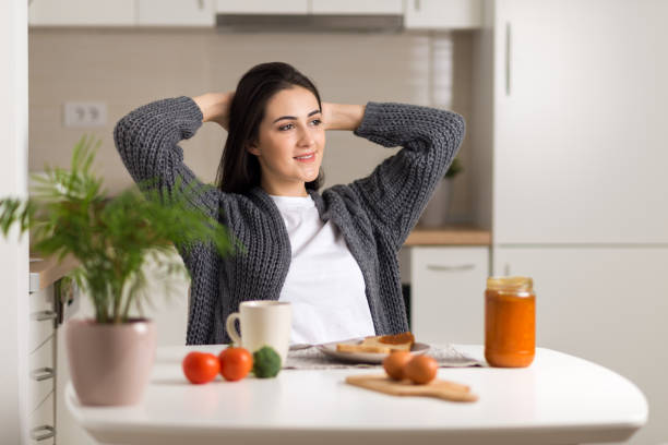 Young woman stretching during breakfast time at home stock photo