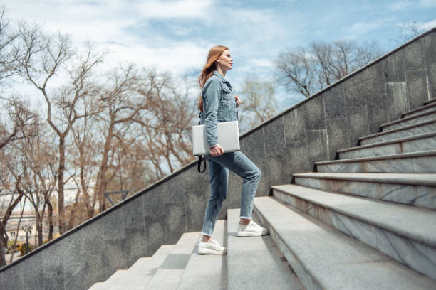Young woman student climbs the stairs up stock photo