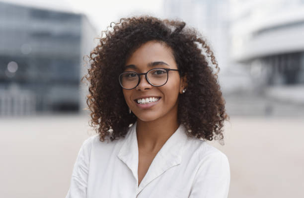 Young woman student outdoor portrait Smiling african-american businesswoman in a city. Mixed race girl looking at camera. People, city life, student lifestyle concept headshot stock pictures, royalty-free photos & images