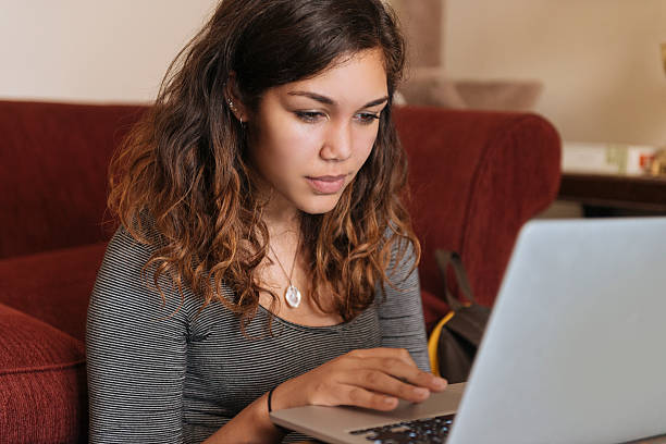 Young Woman Studies On Computer at Home for Higher Education This is a horizontal, color, royalty free stock photograph of a university student in her early 20s studies at home on her laptop computer. The senior in college is a young, millennial woman of Puerto Rican ethnicity. She is doing research online, which is part of everyday modern life as she works towards completing her higher education. Photographed with a Nikon D800 DSLR camera. puerto rican women stock pictures, royalty-free photos & images