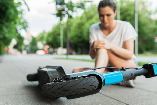 jonge vrouw die aan kniepijn na e-scooter berijdend ongeval lijdt - elektrische step stockfoto's en -beelden