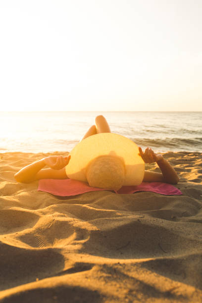 young woman sunbathing on the beach stock photo