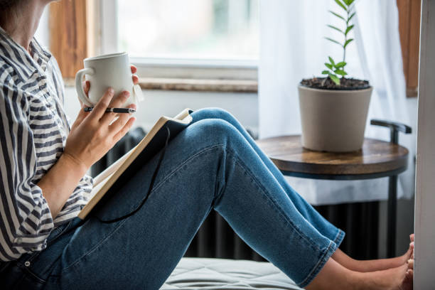 A young woman taking a break from technology A young woman takes a break to do something analog like writing in her journal and drinking tea. This is a healthy practice for those who experience anxiety. mindfulness stock pictures, royalty-free photos & images