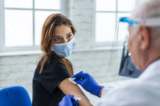 Young woman taking a vaccine from her doctor stock photo