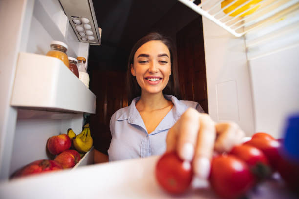 冷蔵庫から新鮮な健康的な野菜を取る若い女性 - 冷蔵庫　中 ストックフォトと画像