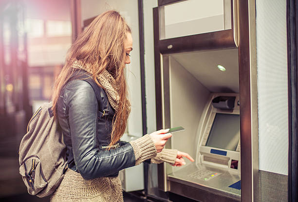 Young woman taking money from ATM Young woman withdrawing money from credit card at ATM bank account stock pictures, royalty-free photos & images