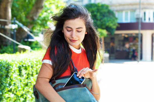 Young woman taking phone out of her purse stock photo