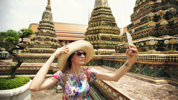Young woman tourist taking selfie with smartphone at temple sightseeing in Bagnkok Thailand during traveling stock photo