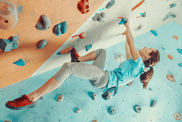 Young woman training in climbing gym Sporty young woman training in a colorful climbing gym. Free climber girl climbing up indoor bouldering stock pictures, royalty-free photos & images