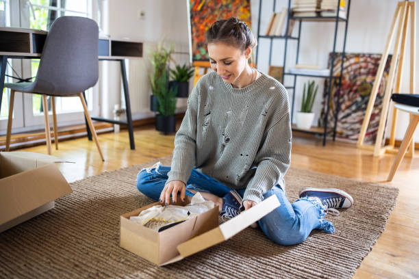 Young woman unpacking package that she have received after online shopping stock photo