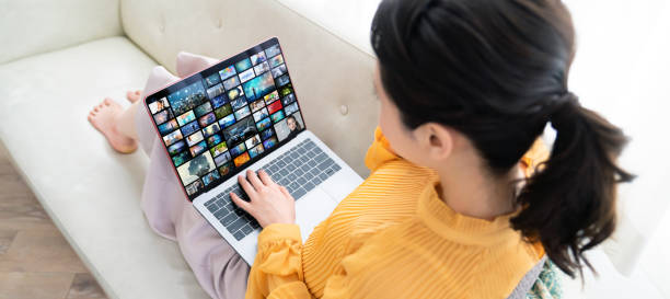 Young woman using a laptop in house. Social media. Streaming video. Young woman using a laptop in house. Social media. Streaming video. downloading stock pictures, royalty-free photos & images
