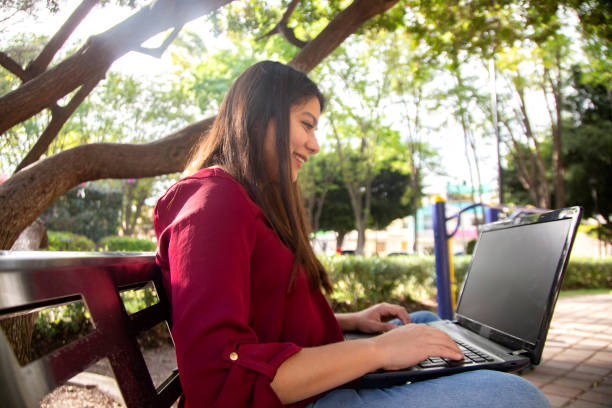 Young woman using laptop in the park stock photo