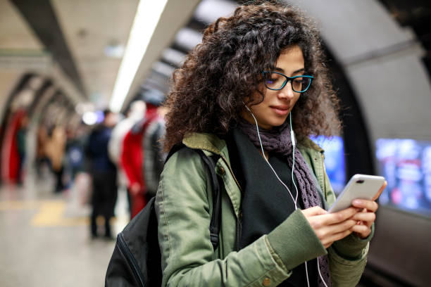jonge vrouw met behulp van mobiele telefoon in het metrostation - arabic student stockfoto's en -beelden