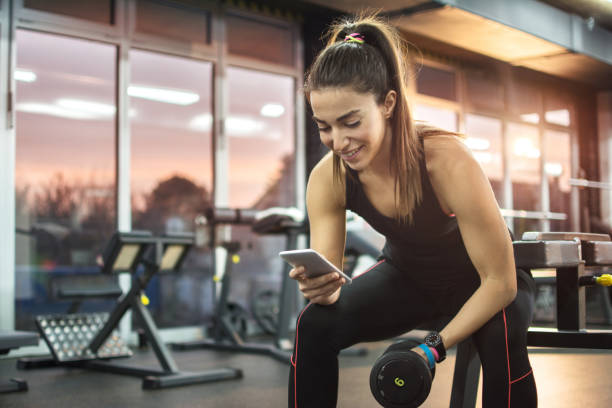 Young woman using phone in gym. stock photo